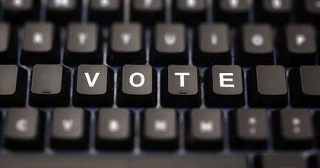 Online voting concept. Vote word written on keypad. Black keys with white letters message for election on pc keyboard. Blur buttons background.の写真素材