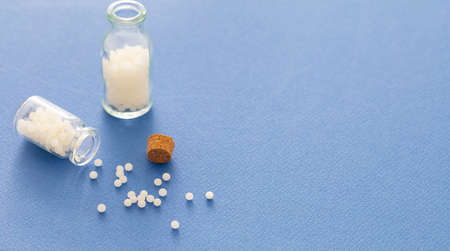 Homeopathy, globules scattered out of glass bottle, blue background. Natural alternative medicine, copy spaceの写真素材