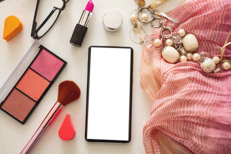 Woman accessories and smartphone with blank white screen against white color background, flat lay, top view. Fashion blogger workspace, copy spaceの写真素材