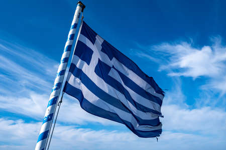 Greece sign symbol. Greek flag on flagpole waving in the wind. Blue sky with white clouds, sunny spring dayの写真素材