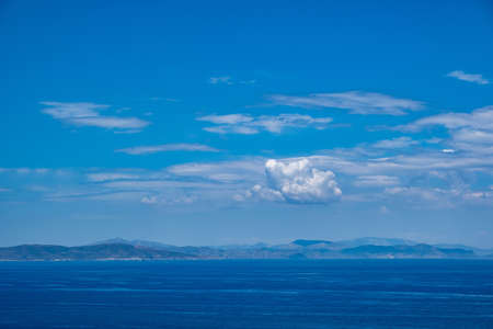 Blue sea and sky background, blue shades horizon. White clouds on clear sky over sea water surface. Tranquil ocean with ripples. Aegean mediterranean sea, Greeceの写真素材