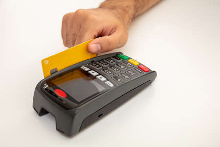 Hand swiping a credit card in a POS terminal isolated on white background, closeup view.Terminal...