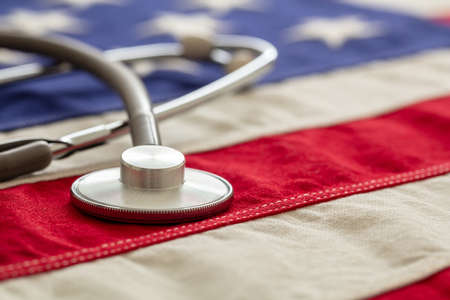 USA health care. Medical stethoscope on a US of America flag, closeup view. American health insurance  conceptの写真素材