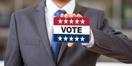 USA elections, Man holding a card, VOTE text message on american flag colors with patriotic stars....