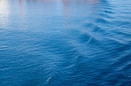 Sea water background. Calm rippled surface with reflections, empty blue color ocean background