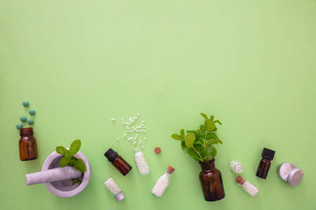 Alternative herbal medicine. Homeopathic globules, fresh mint herb isolated against green...