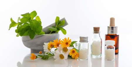 Alternative herbal medicine. Homeopathic globules, fresh wild flowers and herbs isolated against white background. Aromatherapy, Homeopathy natural products