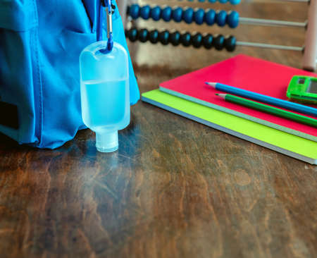 School, coronavirus days. Hand sanitizer gel and school bag backpack on wooden desk background, close up view, copy spaceの写真素材