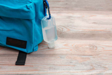 School, coronavirus days. Hand sanitizer gel and school bag backpack on wooden desk background, close up view, Template, copy spaceの写真素材