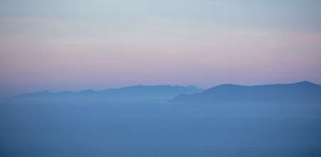 Pastel blue and pink shades on sea and sky background, Aegean Mediterranean sea and Attica Greece hills, view from Kea island at sunset time,の写真素材