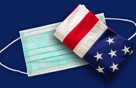 Coronavirus Covid 19 in USA. Protective medical face mask and US of America flag against bleu background.の写真素材