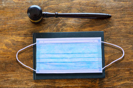 Judge lawyer office desk, coronavirus days. Protective face mask and auction gavel on wooden...