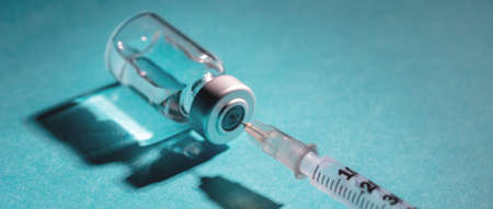 Vaccine, coronavirus vaccination, covid-19 flu prevention, immunization concept. Vial dose and medical syringe, drug medicine shot injection, blue background, closeup.の写真素材