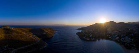 Kea Tzia island, Cyclades, Greece. Panorama of Otzias bay at sunrise. Sun coming up at dawn behind the hills, calm water, aerial view from droneの写真素材
