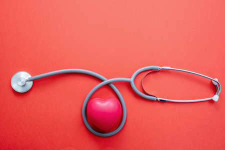 Medical stethoscope on red color background, Health checkup cardio diagnosis, healthcare concept. Heartbeat test tool, cardiology doctor equipment, top viewの写真素材