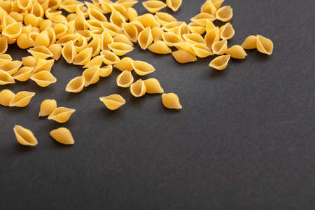 Pasta cooking concept. Fresh homemade shell shape pasta on black stone background, closeup view, copy spaceの写真素材