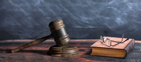 Law gavel, old books and reading glasses on a wooden table, lawyer or judge office desk. 3d...