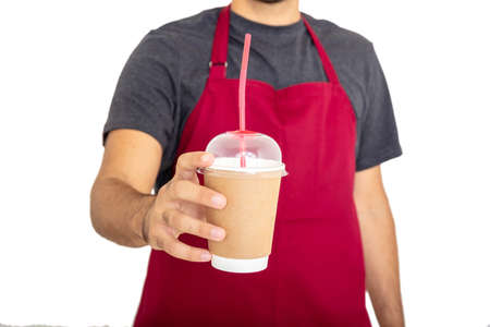 Man offering coffee. Body of young barista with beard and red apron holding a paper container with...
