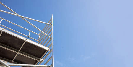 Scaffolding, metal mobile scaffold aginst blue sky background. Under construction, maintenance...