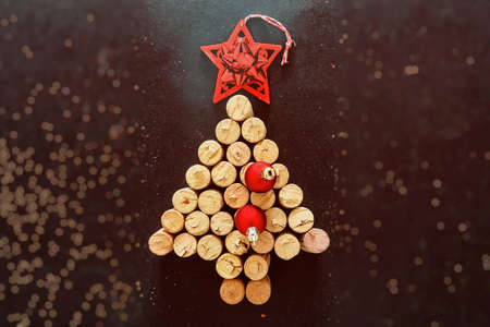 Wine corks Christmas tree with red star and ribbon decoration, bokeh background, top view. New years...
