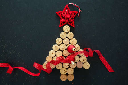Wine corks Christmas tree with red star and ribbon decoration, black background, top view. New years and xmas alcohol drink, holiday party, greeting cardの写真素材