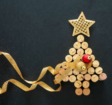 Wine corks Christmas tree with golden star and ribbon decoration, black background, top view. New...