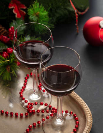 Christmas red wine. Two wine glasses in a silver tray ready to serve, festive xmas ornaments decoration on the table, closeup view. Winter holiday celebrationの写真素材