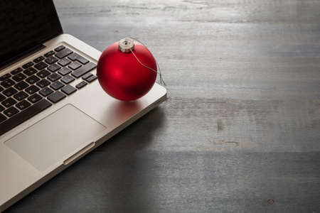 Christmas, office closed. Business desk, holiday card template. Laptop and xmas ornament on blue wooden background, copy space.の写真素材