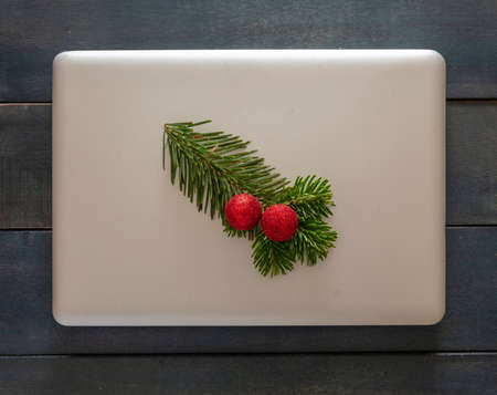 Christmas, office closed. Laptop and xmas ornament on blue wooden background, top view. Computer closed winter holiday season.の写真素材