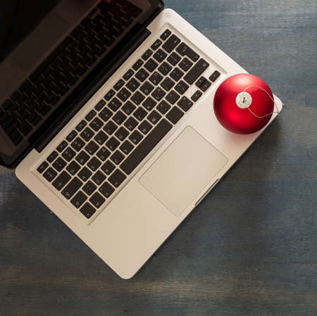 Christmas, office closed. Business desk, holiday card template. Laptop and xmas ornament on blue wooden background, top viewの写真素材