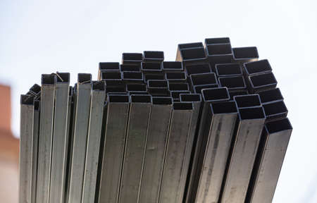 Many metal pipes stacked together on construction site during building works in city. Hollow...