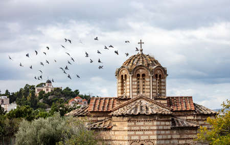 Flock of pigeons flying around the Greek Orthodox church in Thissio area, Athens, Greece. National...