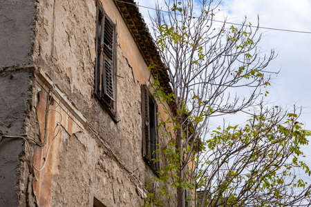 Ruined facade of an abandoned building, cloudy sky background, Plaka, Athens Greece. Low angle viewの写真素材