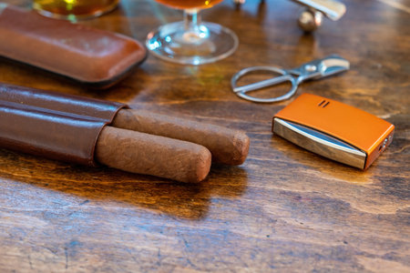 Cigar and accessories on a wooden table, closeup view. Cuban quality cigars and brandy. Tobacco and alcohol, smoking and drinking luxury lifestyleの写真素材