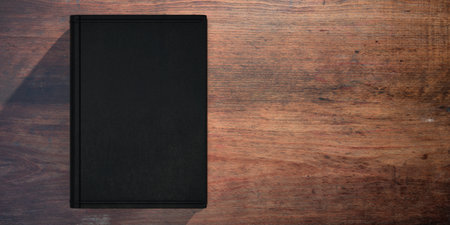 Book blank cover on wooden table background. Closed black cover book template, copy space. 3d...