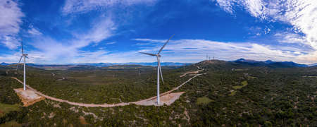 Wind turbines and curvy road on the hill. Wind farm panorama, aerial drone view. Green alternative...
