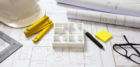 Project blueprints, house model and engineer hardhat white color, Housing project construction, architect site office background.の写真素材