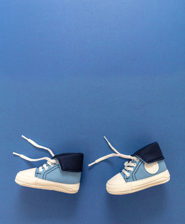 Boy first steps. Baby sport shoes walking on blue color background. Kid small size sneakers, canvas booties. Space, card invitation templateの写真素材