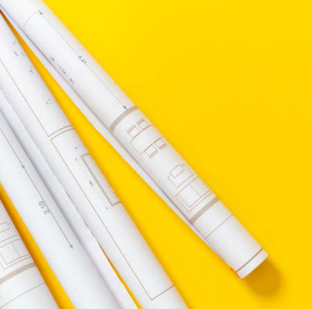 Construction project blueprints concept. Architecture drawings rolls on yellow color background, top view. Architect engineer office, copy space, templateの写真素材