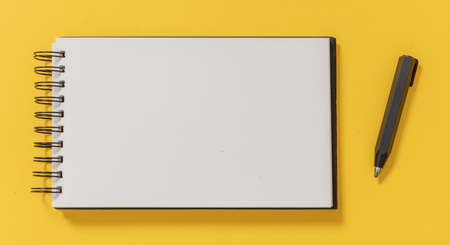 Blank notepad and architect pencil on yellow color background, top view. Opened paper spiral...