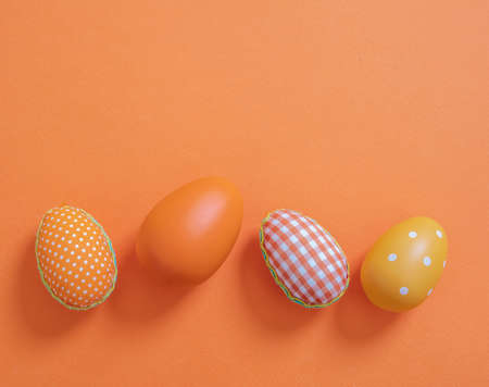 Happy Easter greeting card template. Easter eggs collection on pastel orange color background, top view. Christian religion holiday celebration and decoration.の写真素材