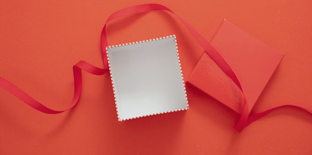 Gift box red and white color on red background, top view. Package open empty with red ribbon, valentine Christmas present surprise concept. Birthday card templateの写真素材