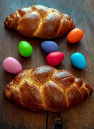 Easter eggs and sweet bread, greek tsoureki, cozonac loaf on wood table background, above view,...