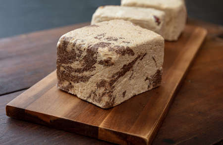 Halva cocoa and sunflower seeds pieces on wooden table background. Chocolate halvah or halwa,...