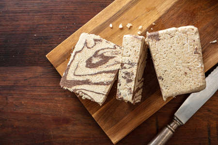 Halva cocoa and sunflower seeds pieces on wooden table background, top view. Chocolate halvah or halwa, traditional dessert confection made also with sesame tahiniの写真素材