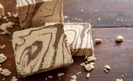 Halva cocoa and sunflower seeds pieces on wooden table background. Chocolate halvah or halwa, traditional dessert confection made also with sesame tahiniの写真素材