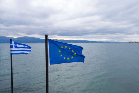 Greek and EU flags waves on the vessel. Where the Greek sea meets the cloudy blue sky. Destination for holiday, travel.の写真素材