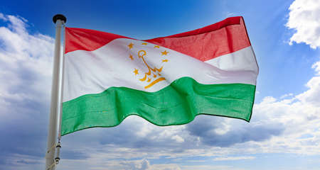 Tajikistan flag, Republic of Tajikistan national symbol on a flagpole waving against blue cloudy skyの写真素材