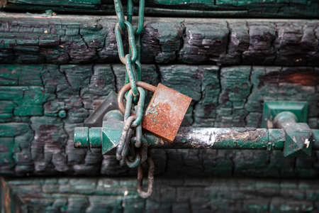 Padlock and metal chain on green color wooden door closeup, closed secured house entrance. Traditional door detail, Plaka Athens Greeceの写真素材