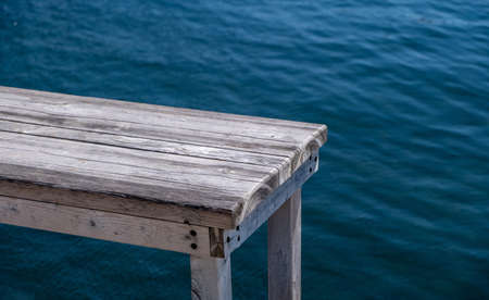 Waterfront empty table, old wooden bench for product presentation, blue sea background, copy space...